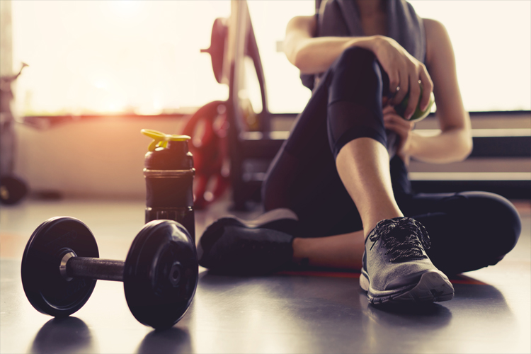 Image of a lady sat next to weights in the gym.