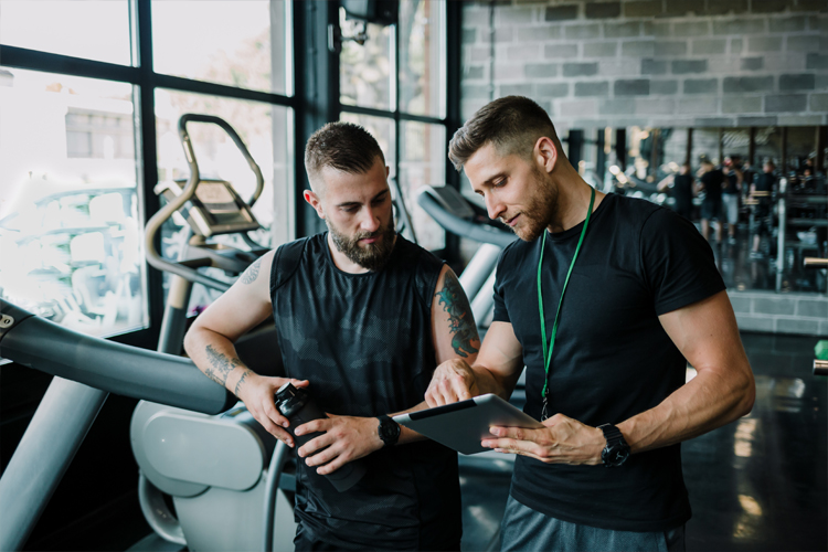 Image of a personal trainer at the gym coaching a male.